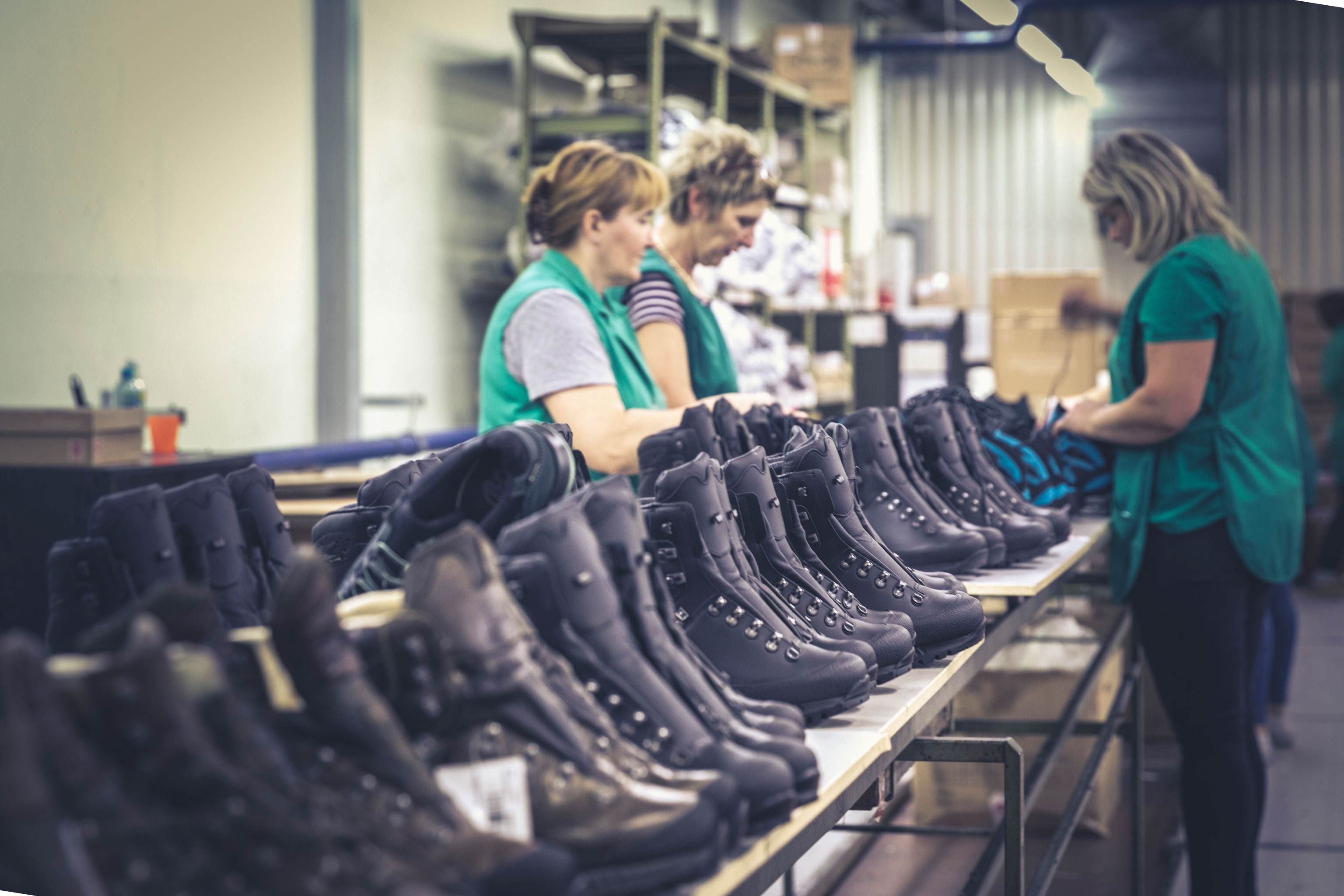 Drei Mitarbeiterinnen der Hanwag Produktion in Kroatien beim Einfädeln von Schnürsenkeln
