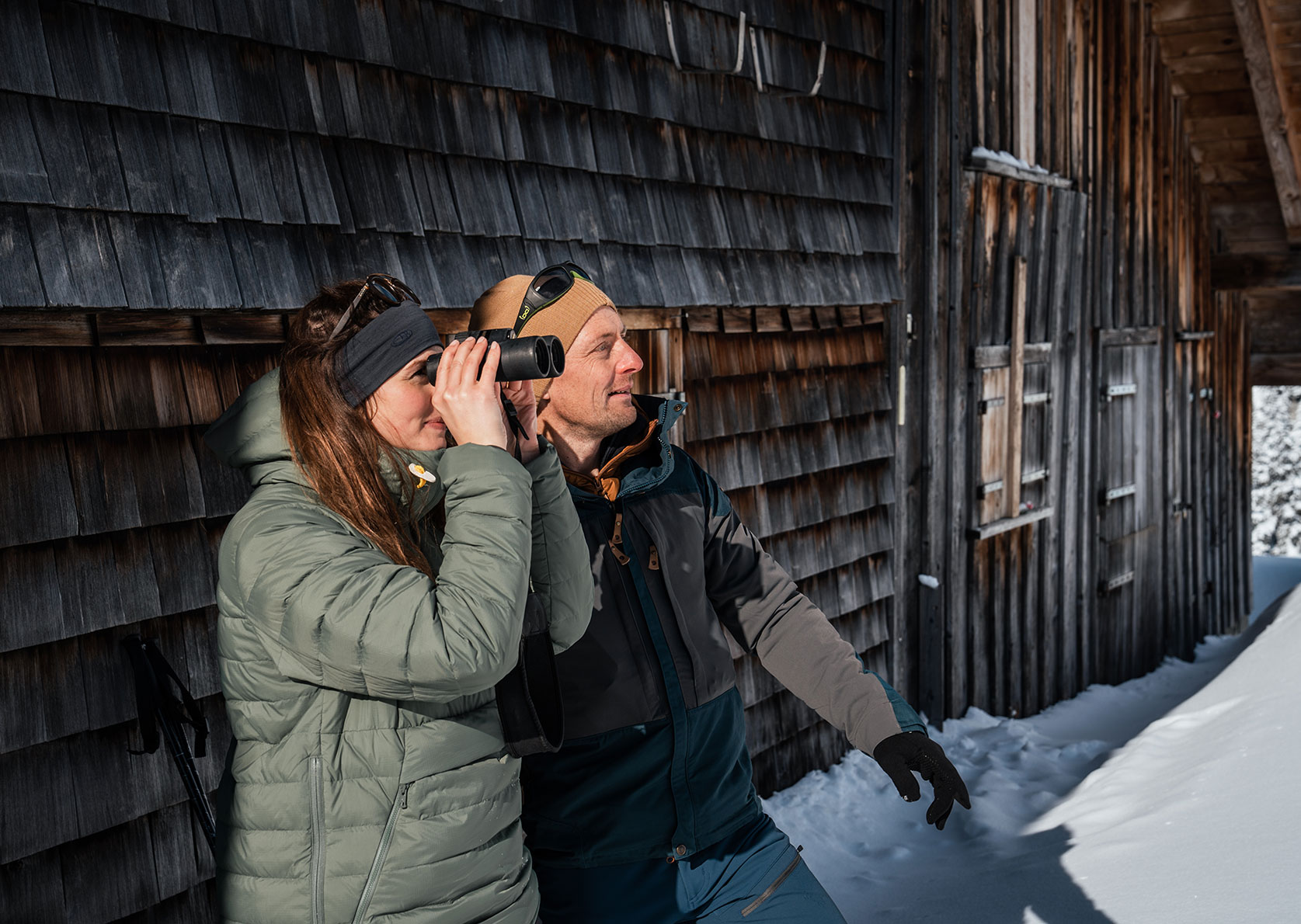 Lukas and Franziska use binoculars to observe chamois in front of a hut