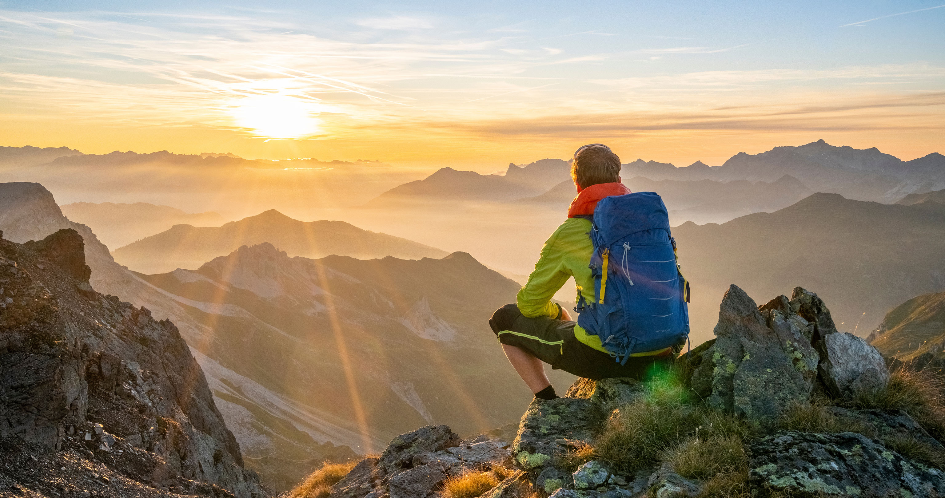 Mann bei Alpenüberquerung betrachtet den Sonnenaufgang