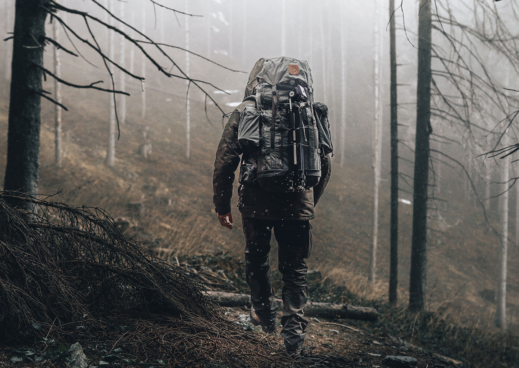 Alex Wander geht beim Bushcrafting mit großem Rucksack durch einen nebligen Wald