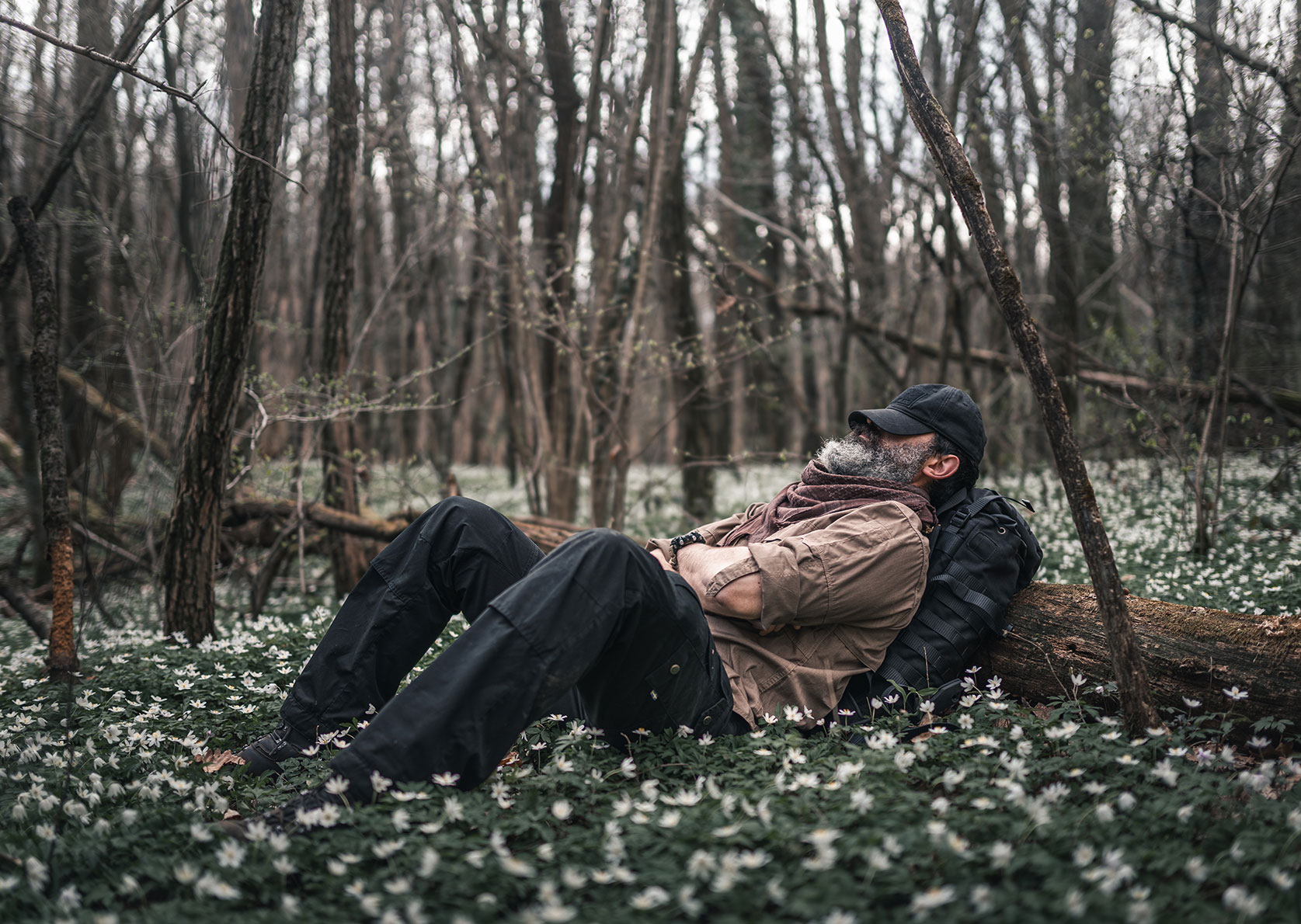Bushcraft skills expert Alex Wander lying on a carpet of flowers on the forest floor and enjoying nature demonstrating bushcraft meaning