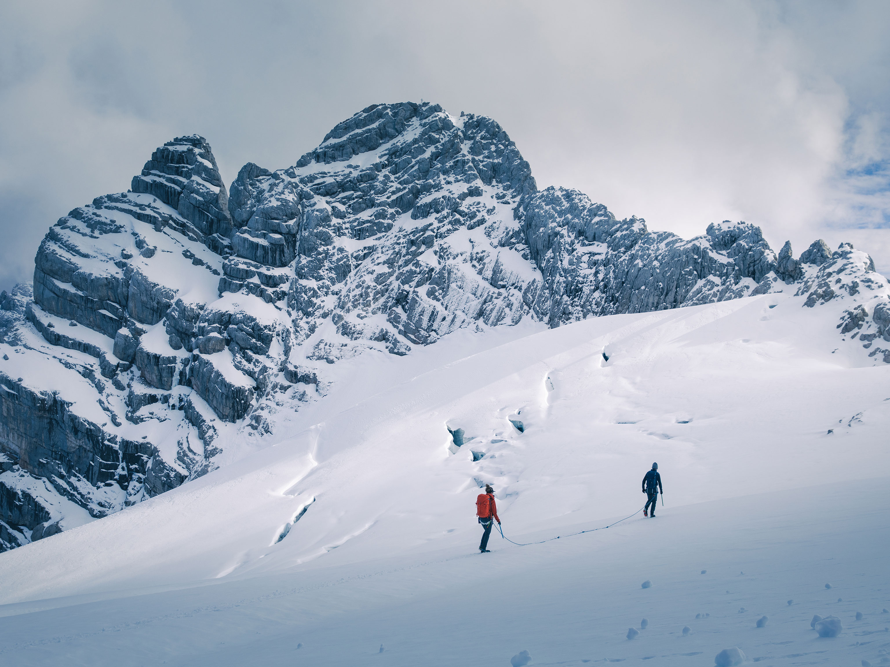 Zwei Bergsteiger gehen angeseilt auf einem Gletscher