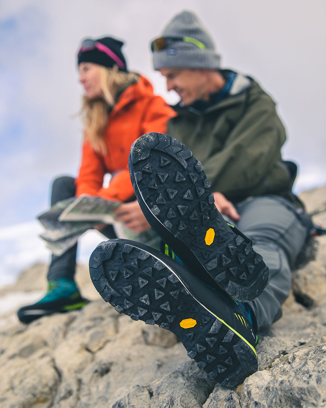The sole of a mountain boot with two mountaineers in the background