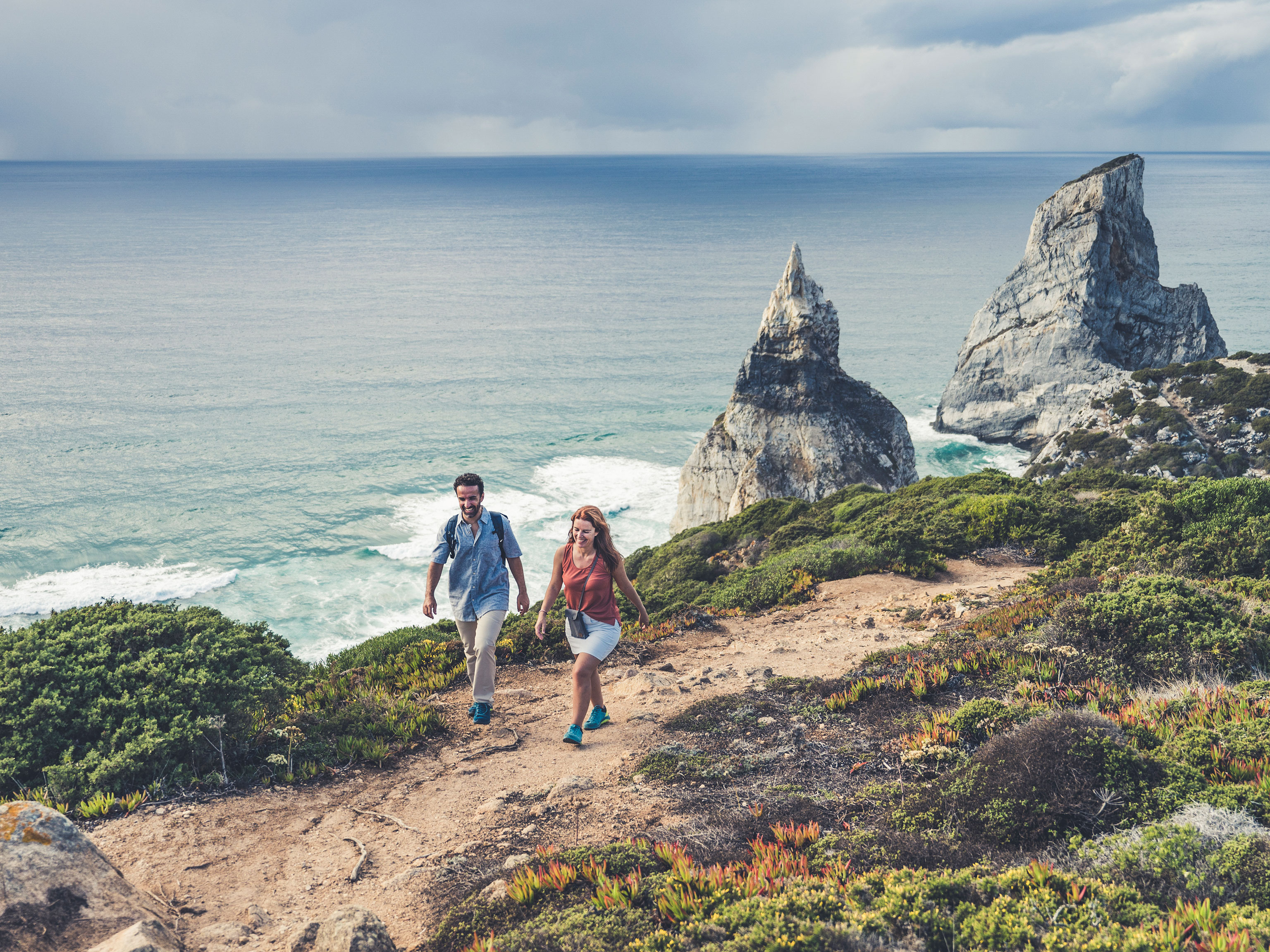 Sintra hiking trail on a coastal footpath along Praia da Ursa with steep rock columns jutting out from the surf