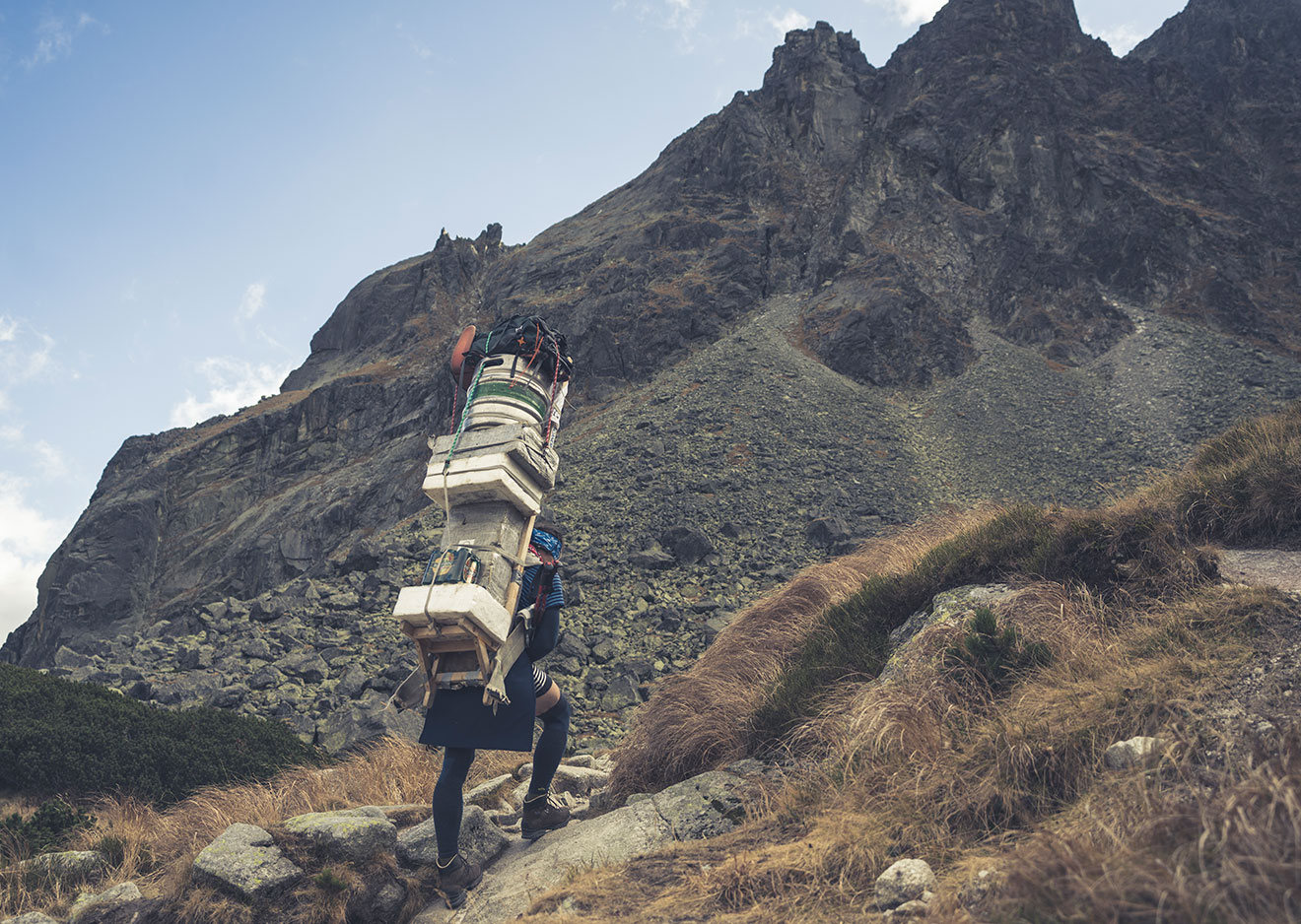 A Tatra Sherpa carrying his frame pack before a rocky ridgeline