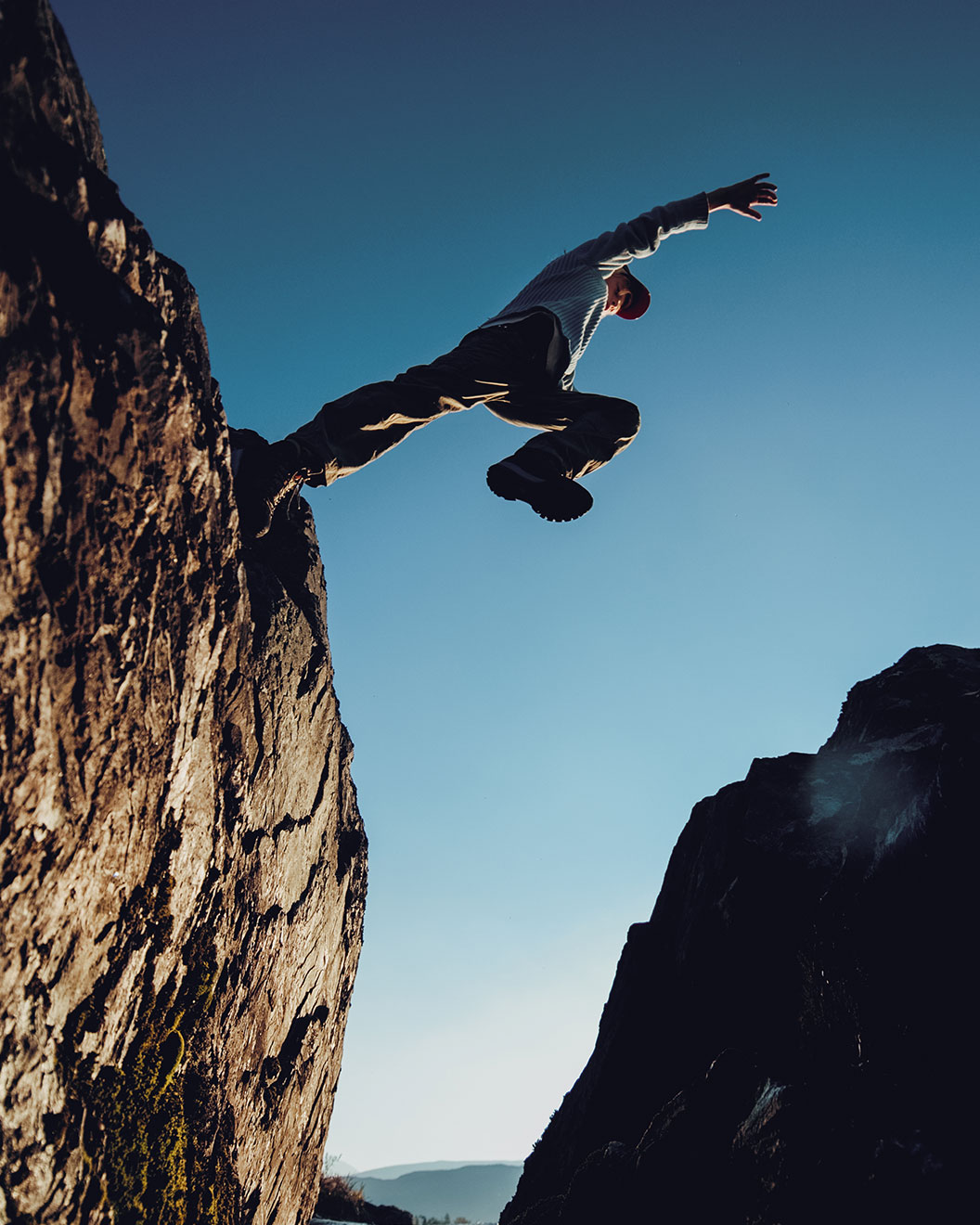 Eine Frau springt im Jotunheimen Nationalpark über eine Felsspalte