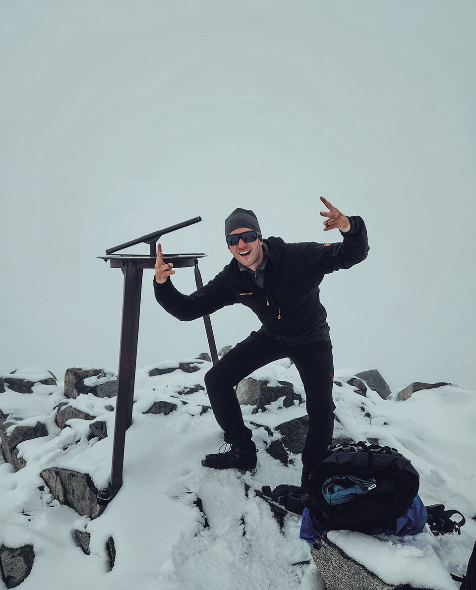 Ein Bergsteiger am verschneiten Gipfel des Galdhoppigen