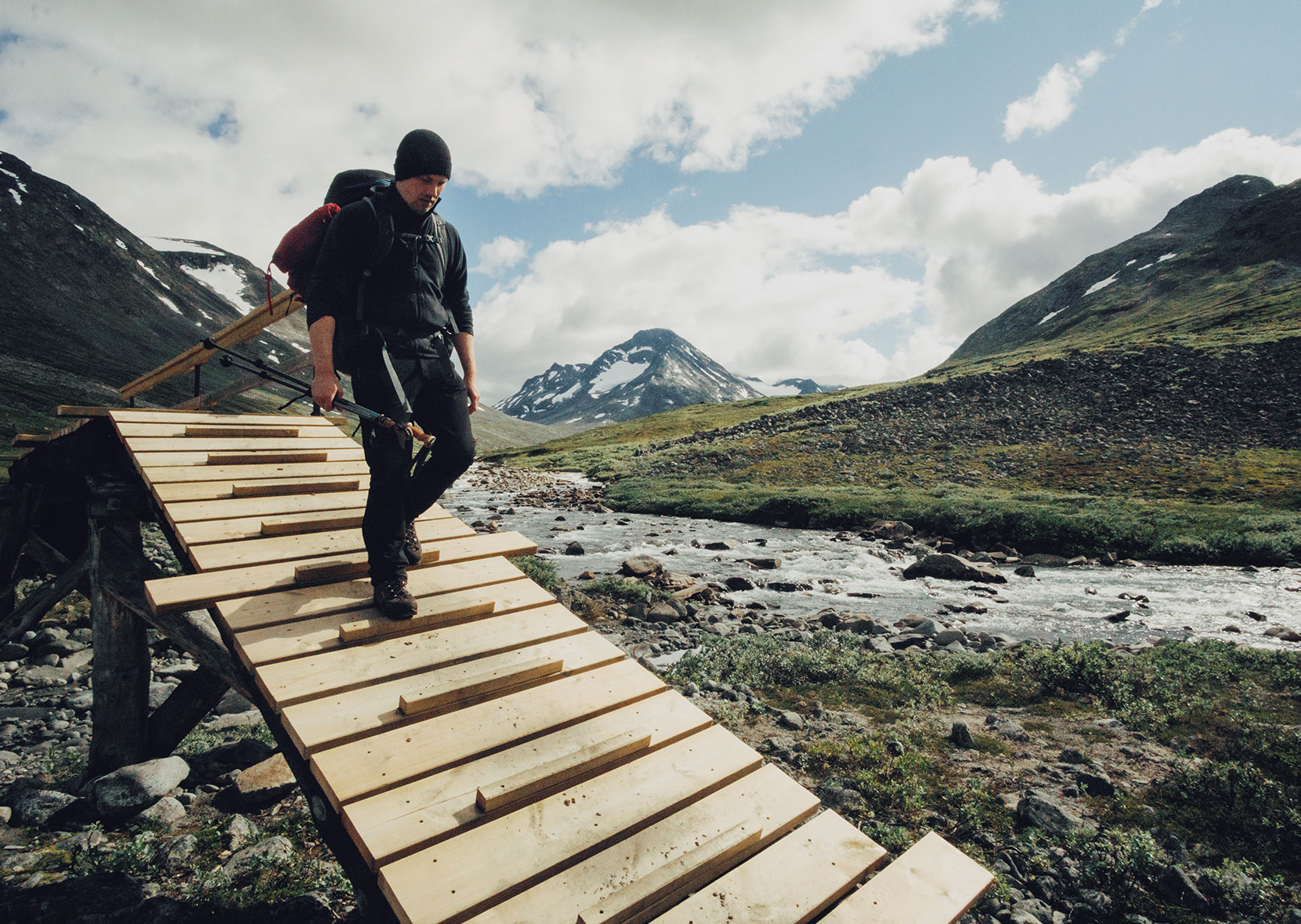 Ein Wanderer auf einer Holzbrücke beim Trekking im Jotunheimen Nationalpark in Norwegen