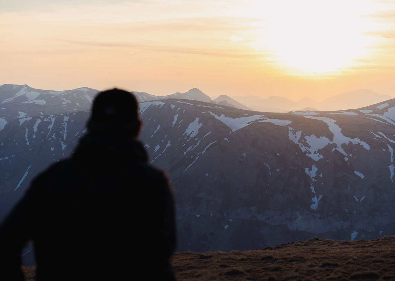 A mountaineer at the summit looking out at the rising sun