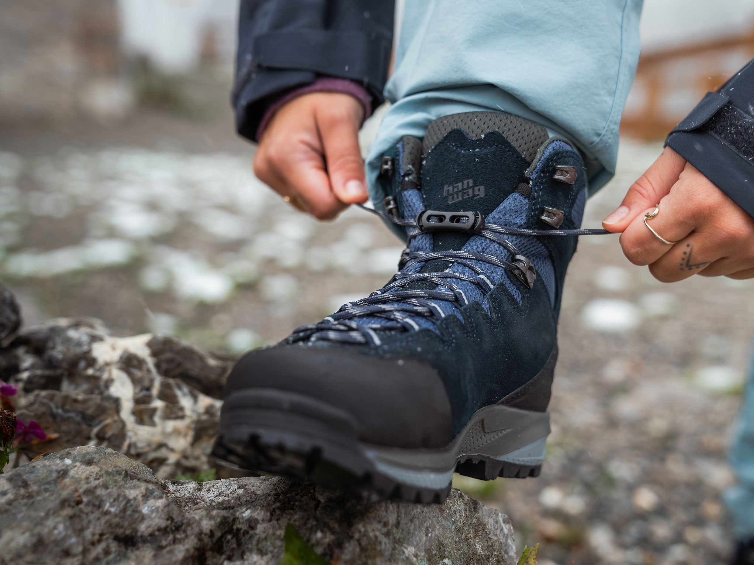 A woman laces up her hiking boots as she breaks them in