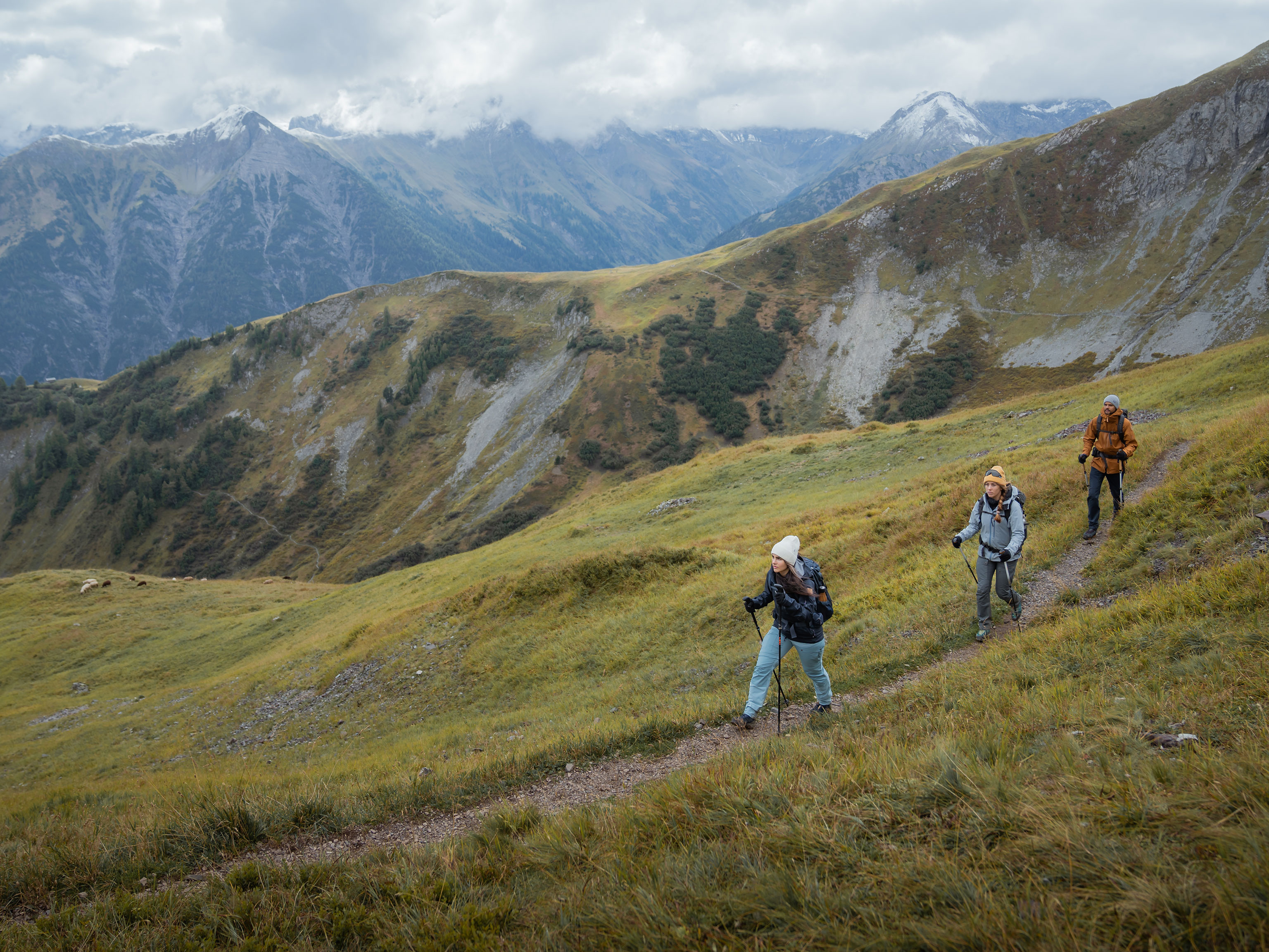 Three hikers walk along a mountain path
