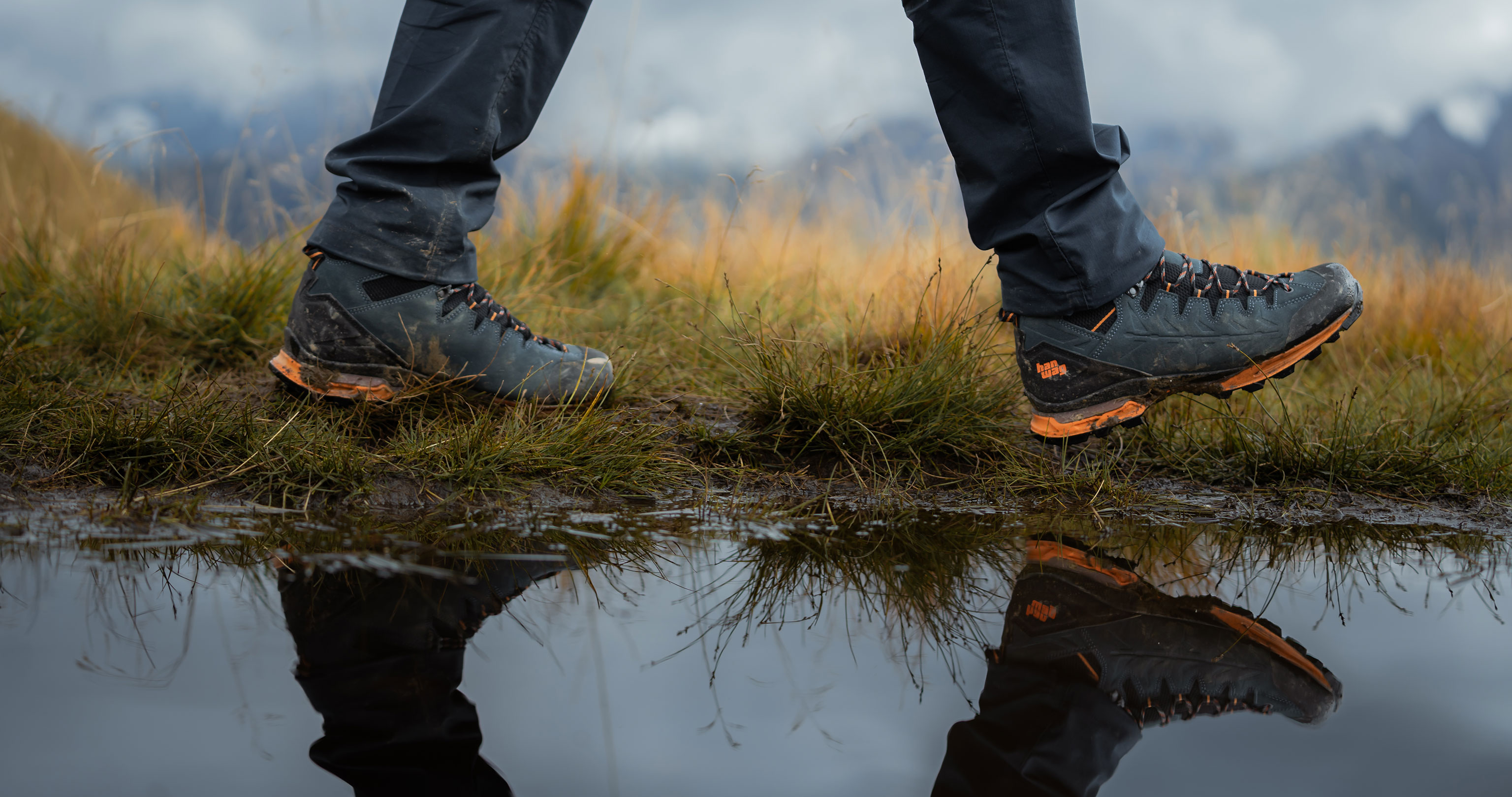 A pair of hiking boots on a run-in tour at the edge of a pond